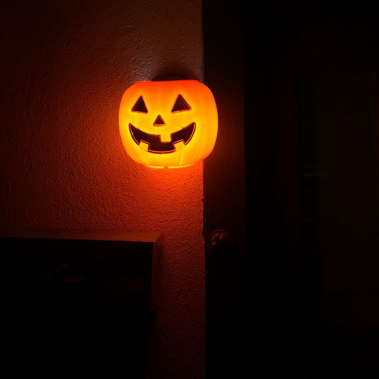 Make a glowing pumpkin sconce by putting $1.00 plastic pumpkin over outdoor lights