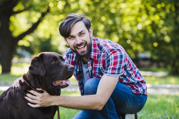 Man smiling in wooded park with his labrador.
