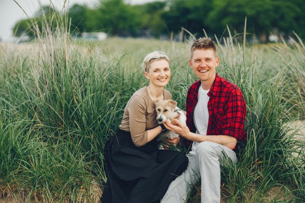 Couple in the woods holding dog and smiling