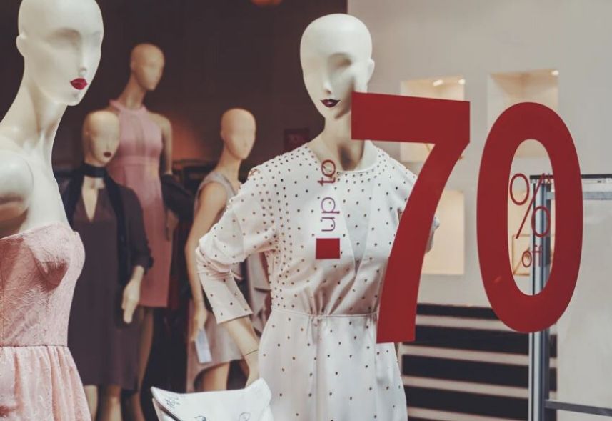 Clothing store marketing: Image of a store window with several mannequins inside the store and 70% off text written on red ink glass.