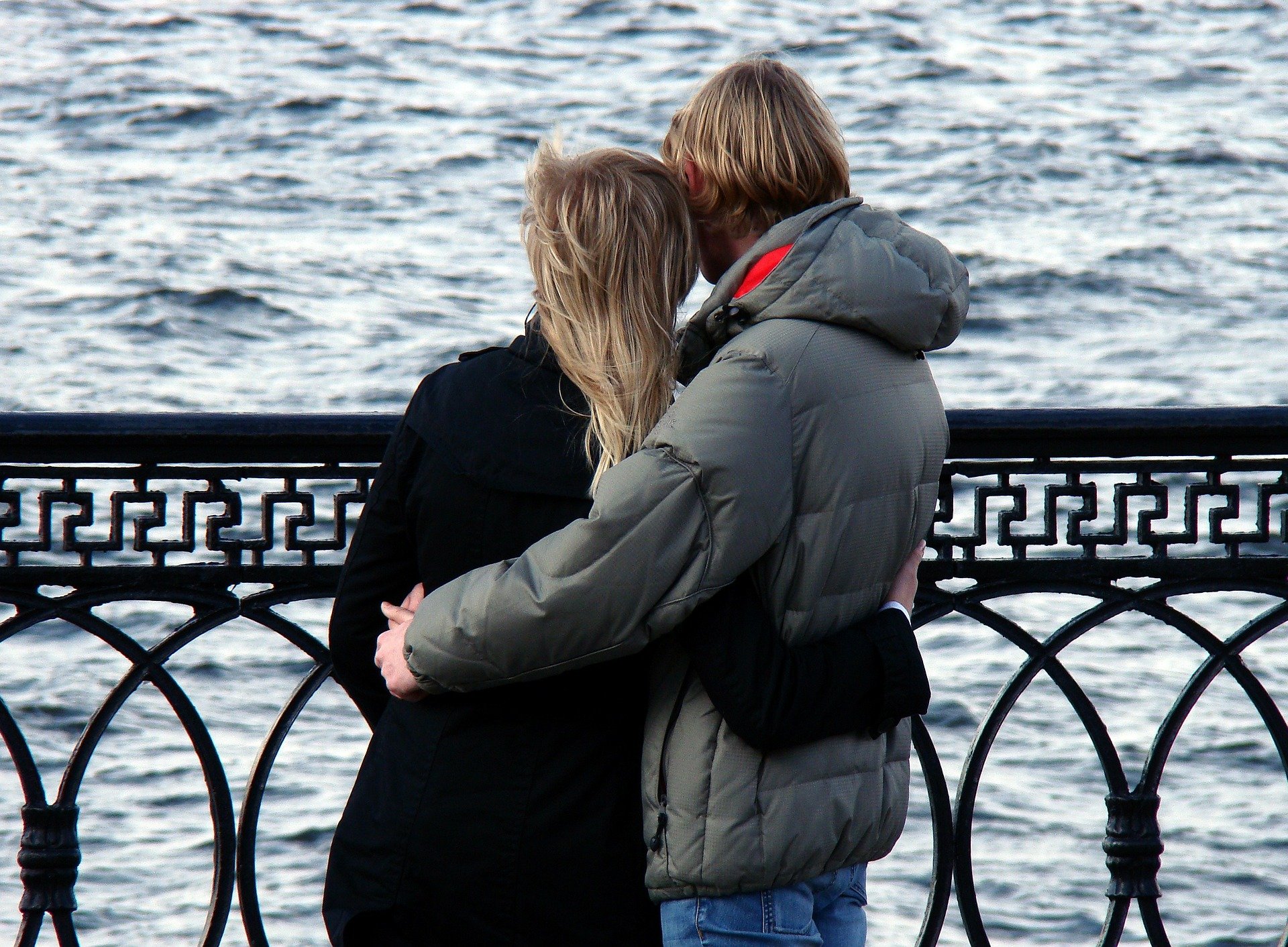 Man and woman hugging each other and looking at the sea.