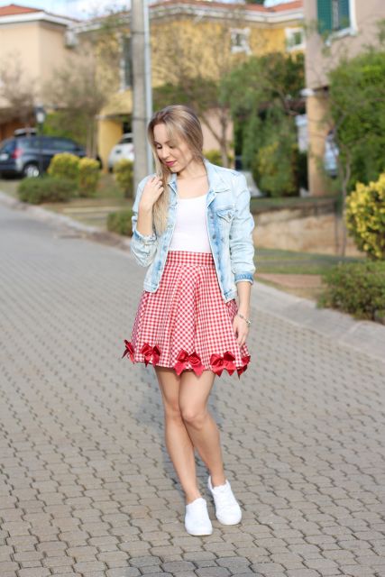 Model wears red plaid pleated skirt, white t-shirt and jacket with sneakers.