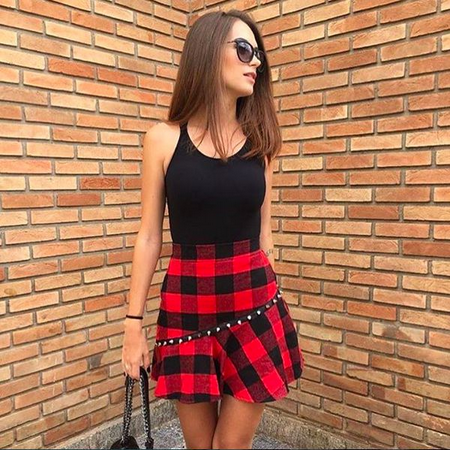 Model wears red and black plaid skirt with black blouse.