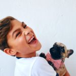 boy laughing and holding dog with funny tie